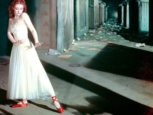 Red Shoes film image. Ballerina in a hallway wearing read shoes and a white dress