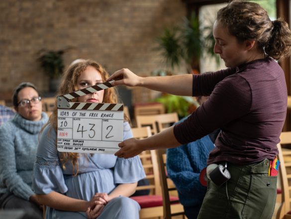 A woman holding a clapperboard in front of an actress on the shoot for Lord of the Free Range