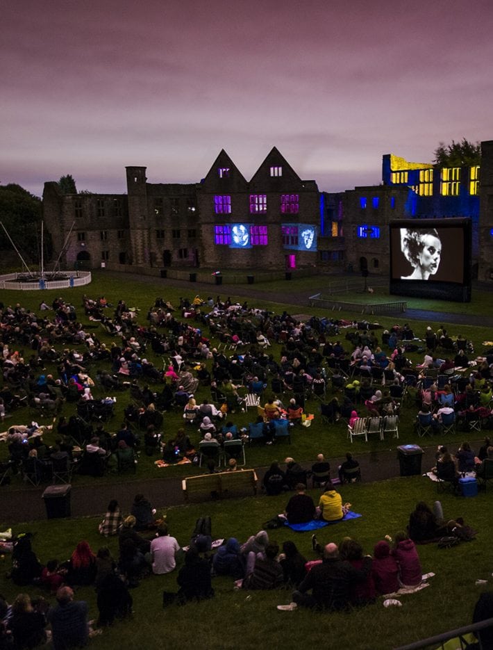 A sea of people are watching a film on an inflatable screen at Dudley castle