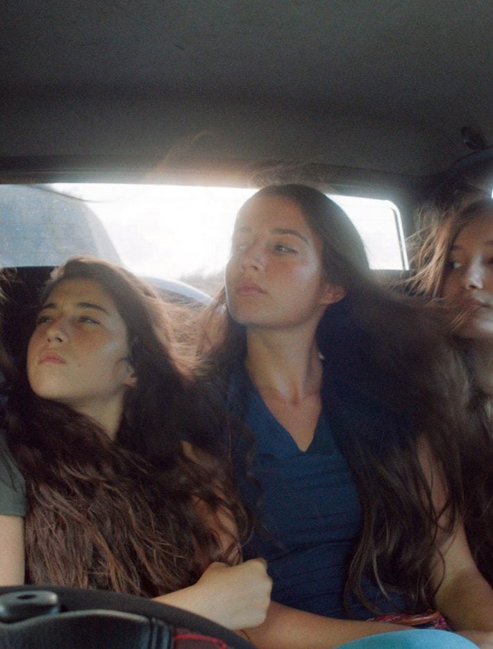 Five young women in the back of a moving car.