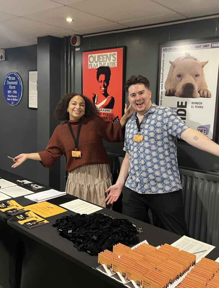 BFI FAN CON behind the welcome desk with open arms