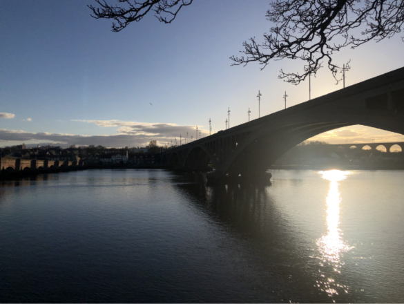 A Bridge reaches across a body of water sunlight reflecting off of the surface